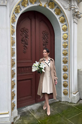 a lady in a beige dress and a brown trench coat